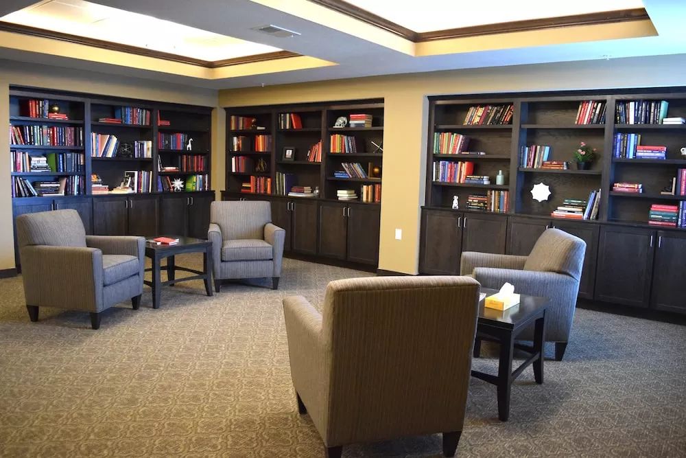 A cozy library room with armchairs and bookshelves.