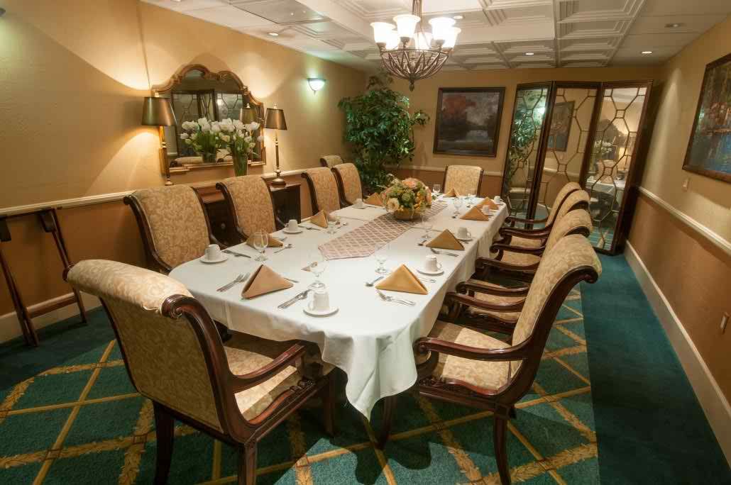 An elegantly set dining room table surrounded by upholstered chairs, featuring a chandelier and tasteful decor.