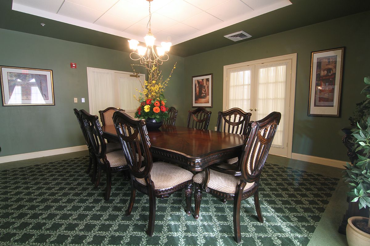 A well-decorated dining room featuring a large wooden table with chairs, a chandelier, and an elegant carpet.