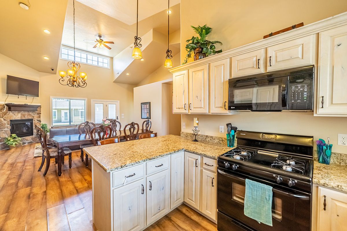 A modern open-concept kitchen with white cabinets, granite countertops, and a view of the dining area.