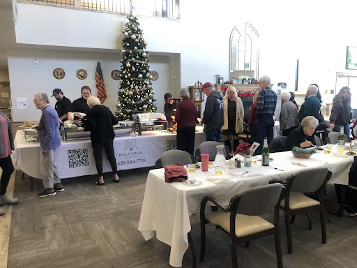 A festive gathering with a Christmas tree, where guests line up to enjoy a meal together.