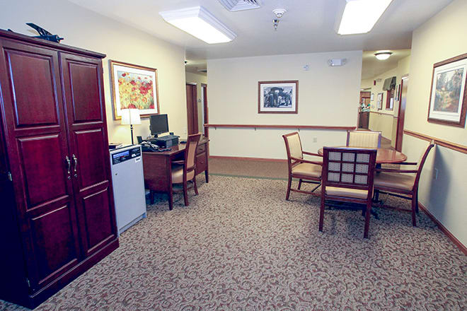 A furnished office space with desks, chairs, and artwork on the walls.