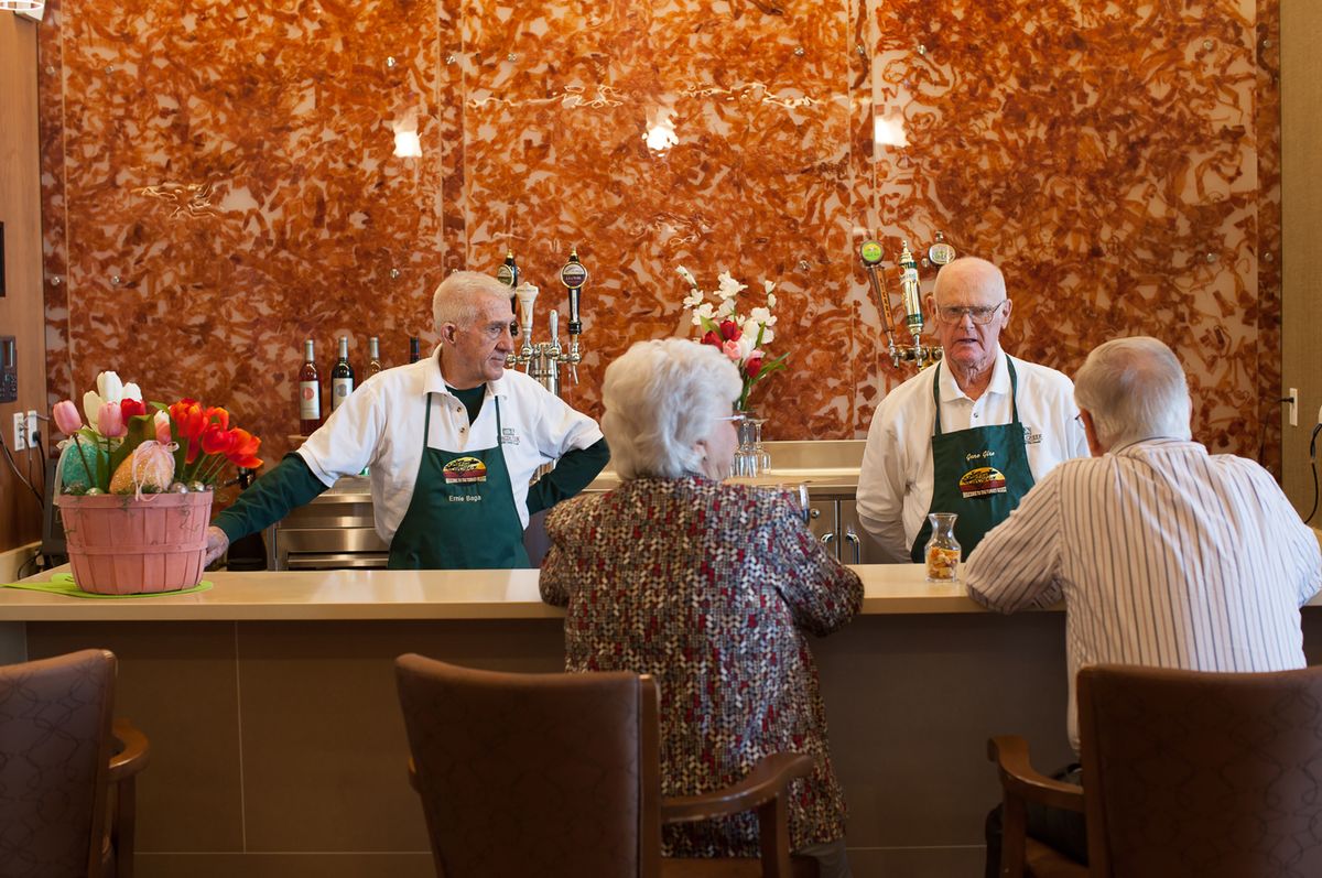 Seniors enjoying a conversation at a bar with two bartenders.