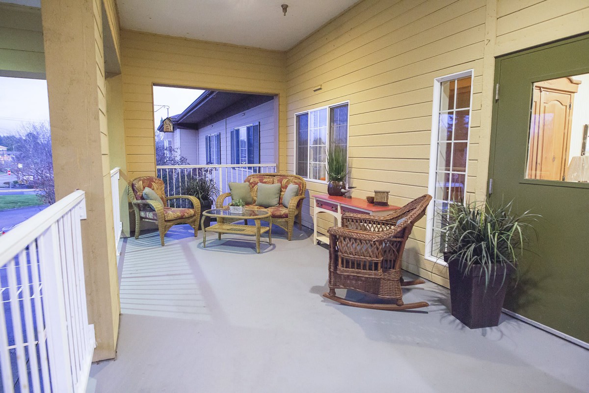 A cozy patio with wicker furniture and decorative plants.
