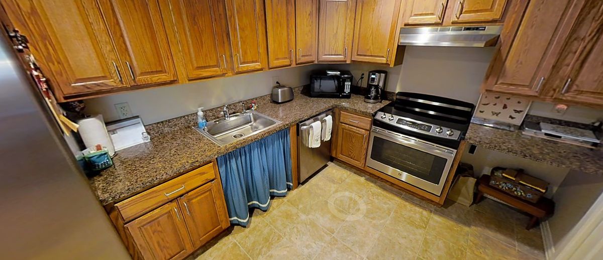 Modern kitchen with wooden cabinets, granite countertops, and stainless steel appliances.