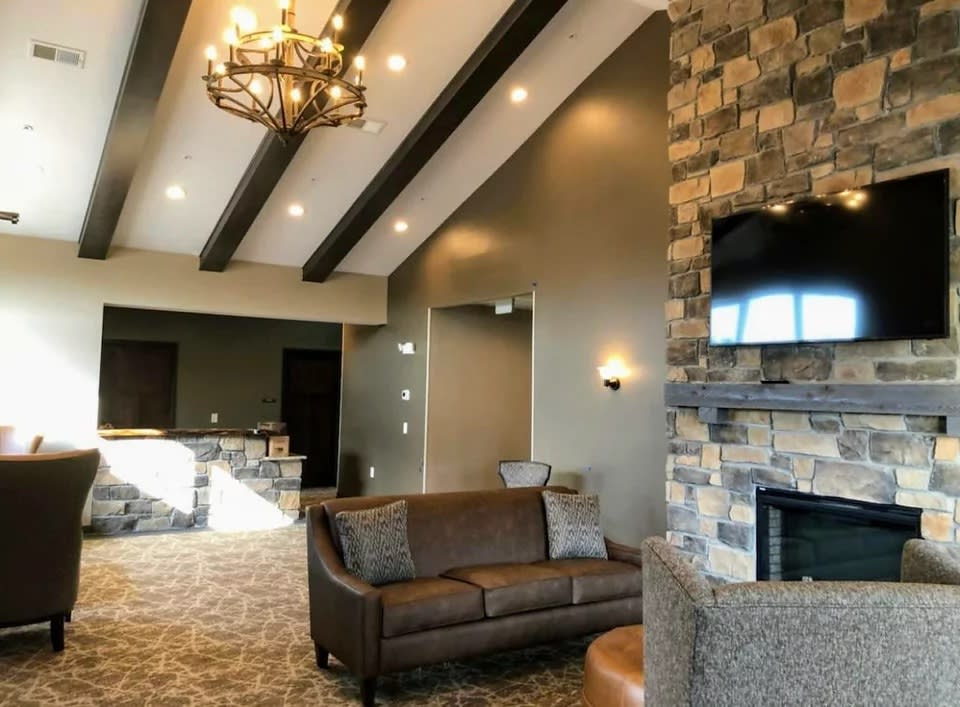 A modern living room with a stone fireplace and beamed ceiling.