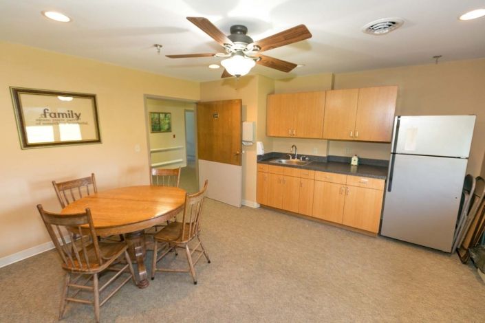 A cozy kitchen and dining area with wooden cabinets, a ceiling fan, and a round table with chairs.