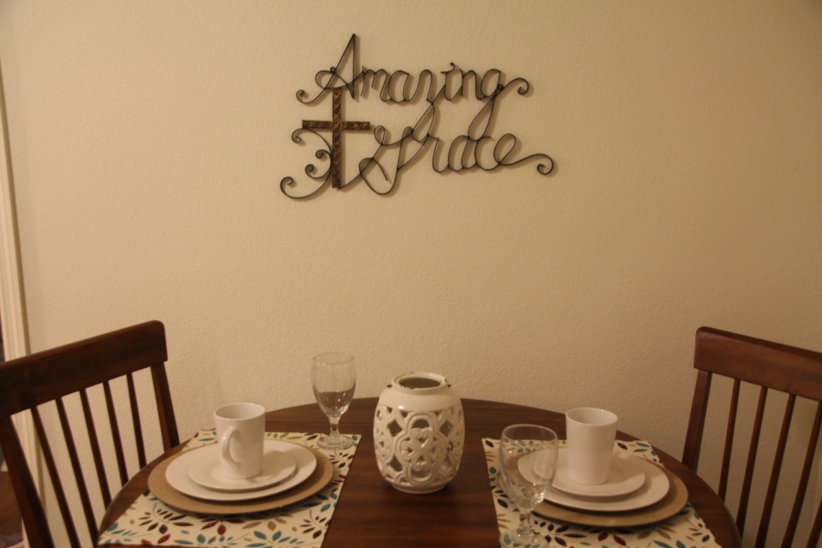 A cozy dining setup with elegant place settings and decorative wall art reading 'Amazing Grace'.