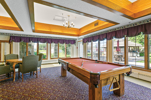 A spacious game room featuring a billiards table and large windows that invite natural light.