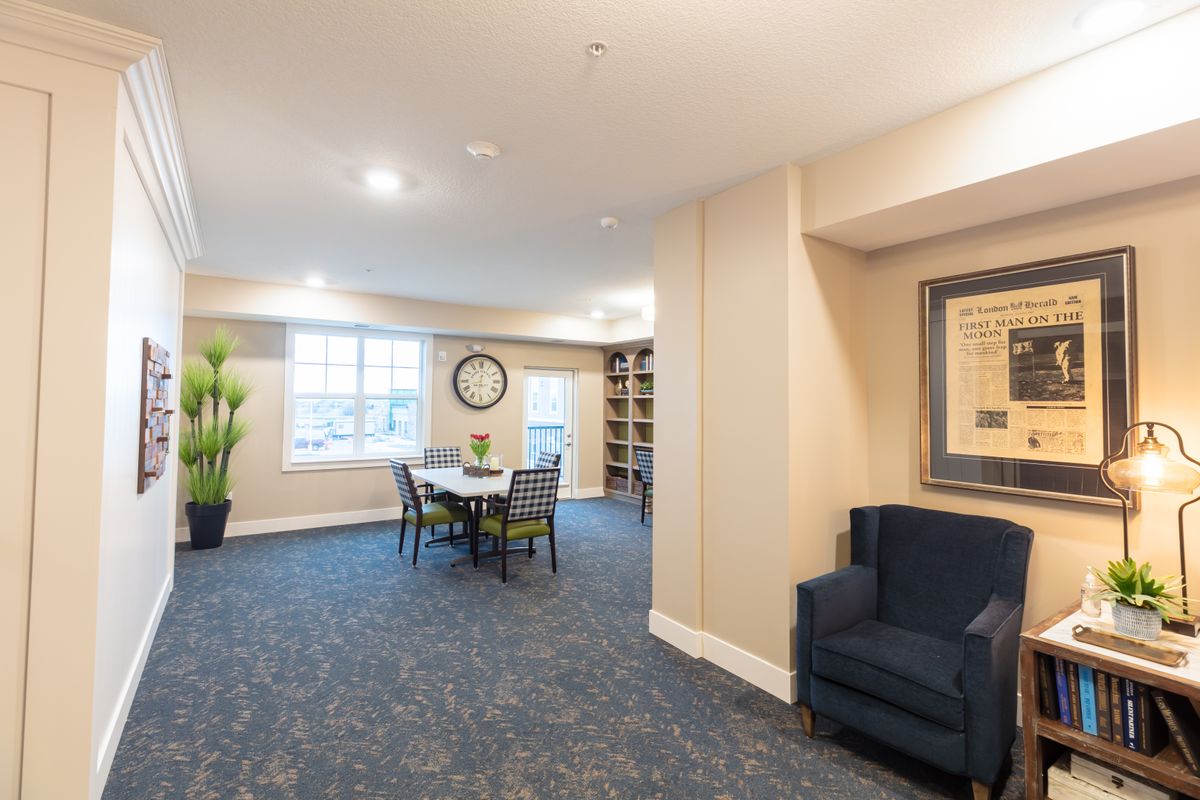 A well-lit room with a seating area, artwork, and a large clock on the wall.