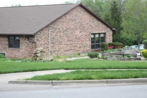 A suburban brick house with a well-maintained lawn and garden.