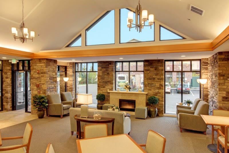 A modern living room with stone walls, a fireplace, and large windows providing natural light.
