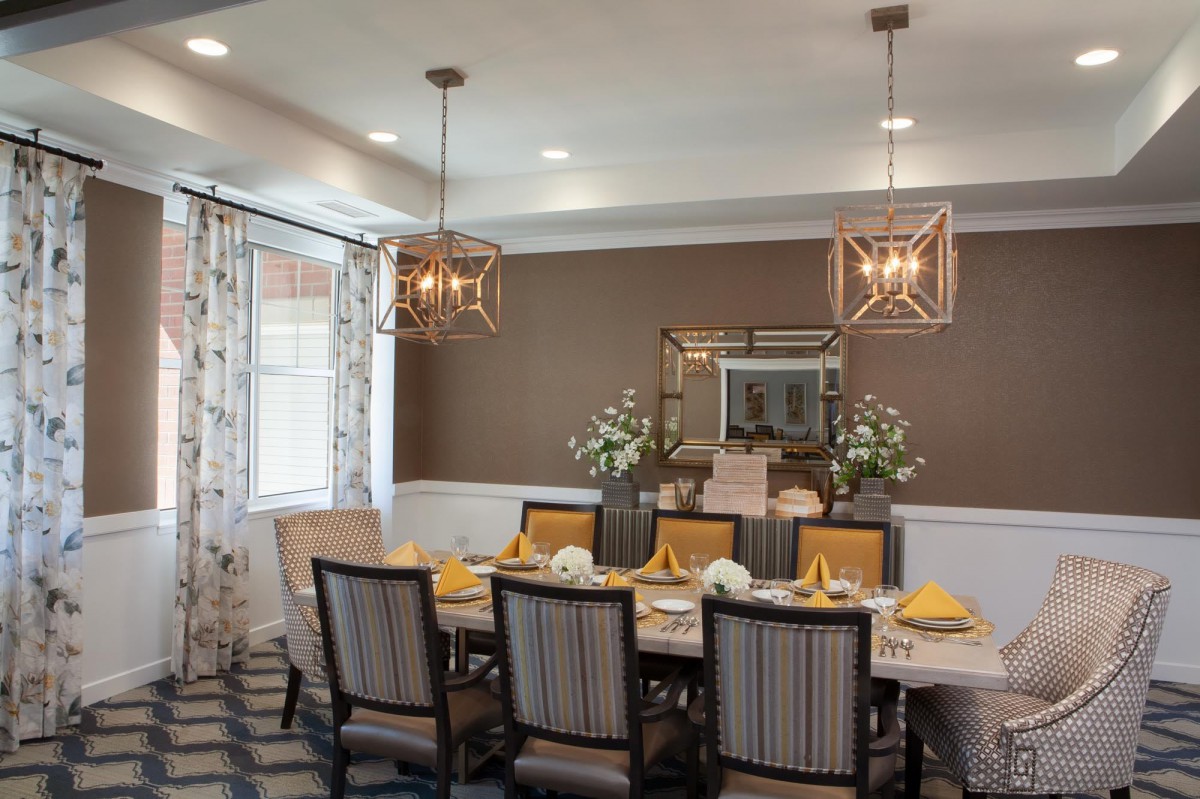 A modern dining room with stylish chandeliers, a large table setting, and elegant decor.