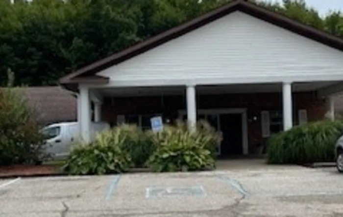A building entrance with surrounding plants and a parking area.