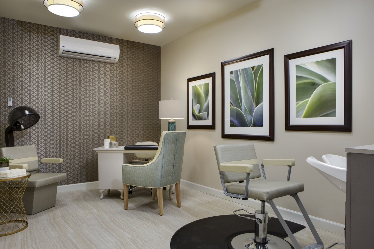 A modern office space featuring a desk, comfortable chairs, and framed artwork.