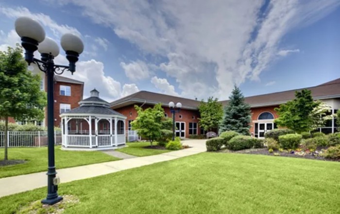 A well-maintained lawn with a gazebo and modern building under a partly cloudy sky.