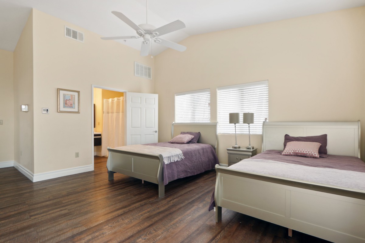 A spacious bedroom with twin beds, featuring natural light and minimalist decor.
