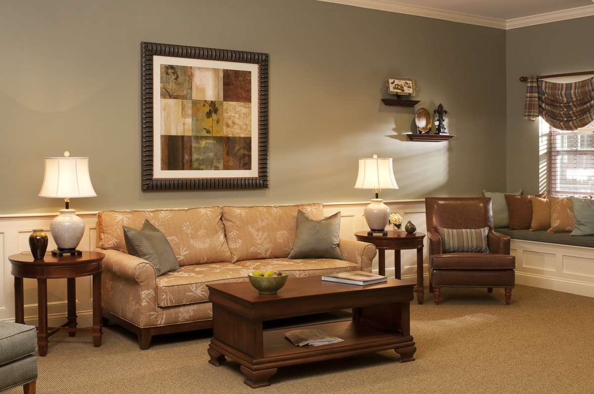 A cozy living room with a sofa, coffee table, and armchair, adorned with elegant wall art and warm lighting.