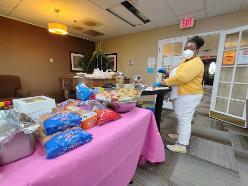 A community member organizes a food distribution table filled with snacks and treats during an indoor event.