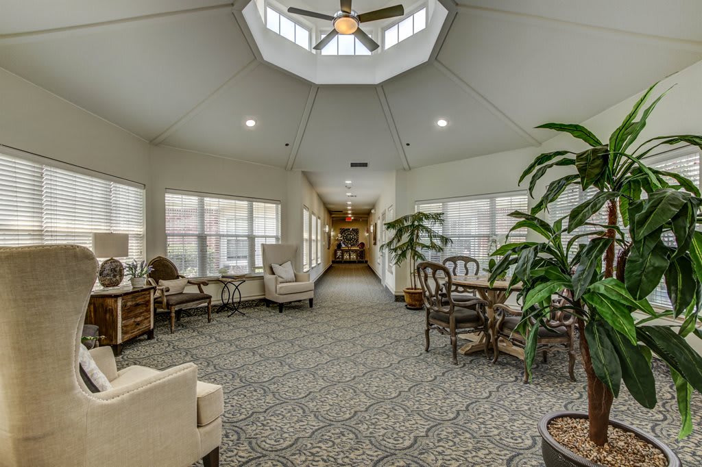 A spacious and well-lit interior living area with comfortable seating, greenery, and large windows.