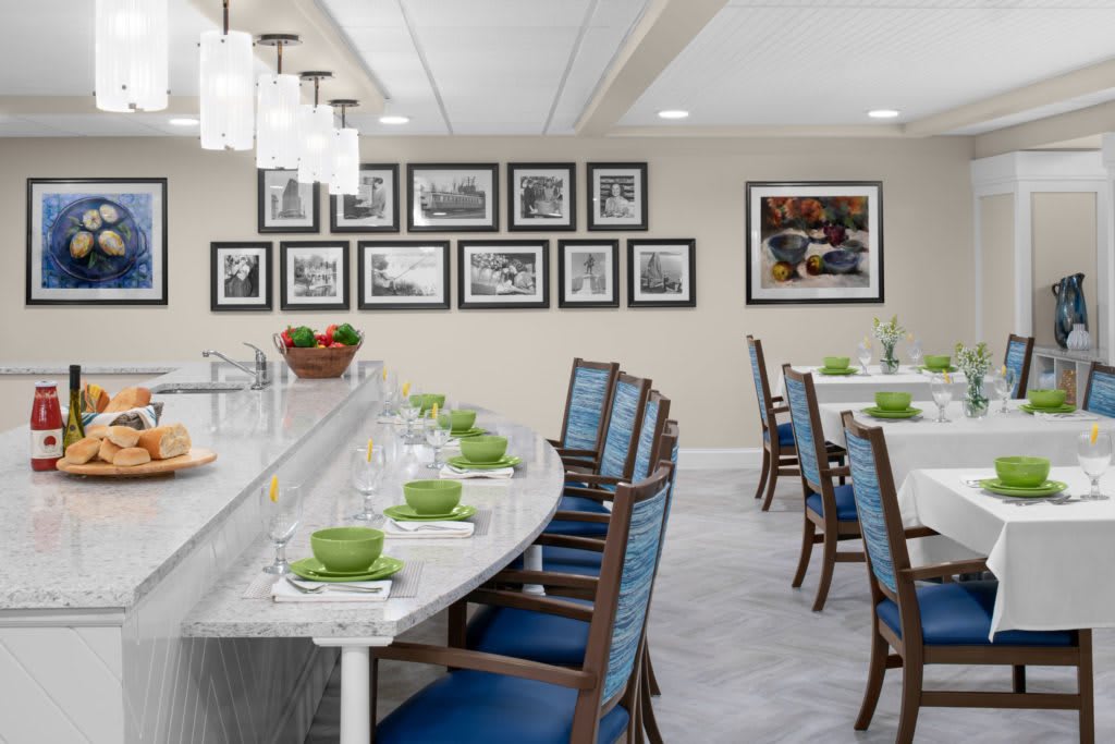 A modern dining room with neatly arranged tables and chairs, featuring framed wall art and elegant table settings.