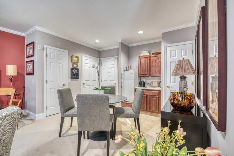 A modern dining area with a table and chairs adjacent to a compact kitchen.