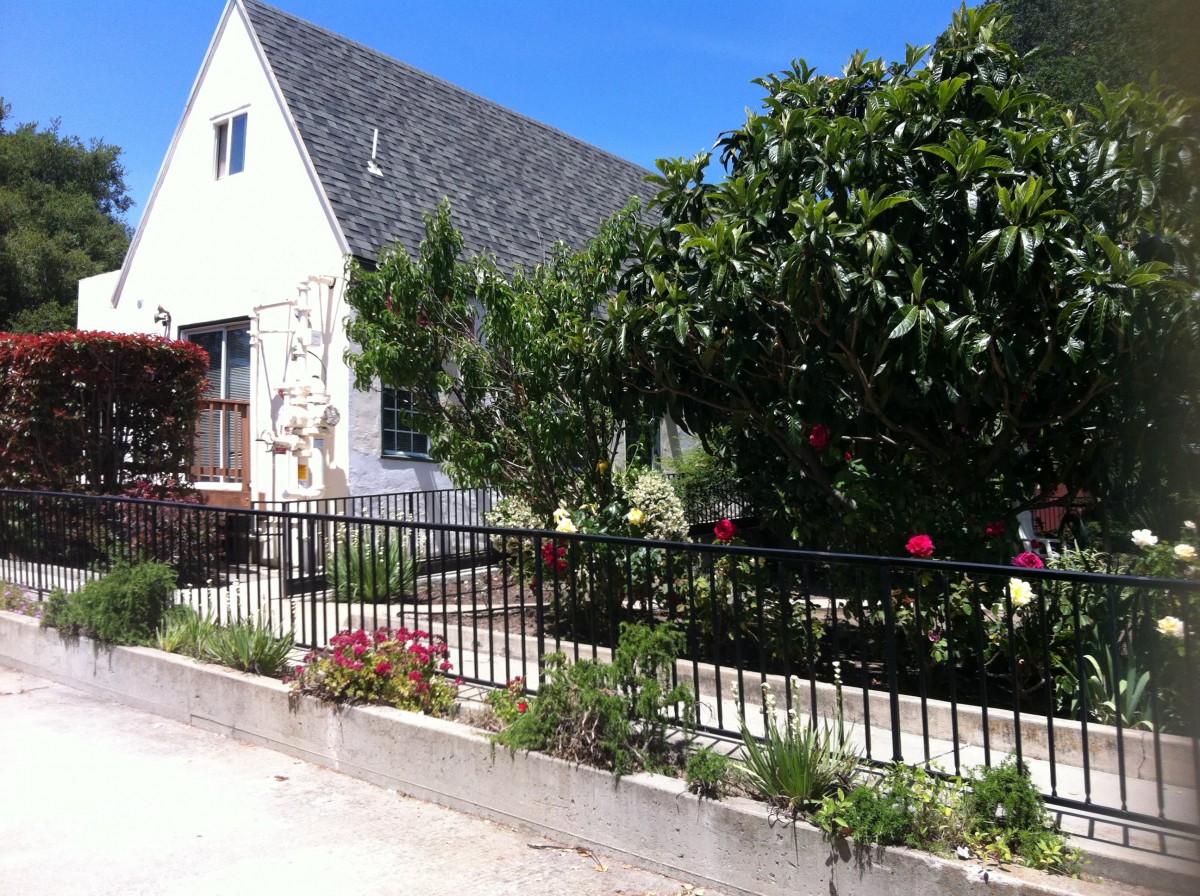 A charming house with a lush garden and fence on a sunny day.