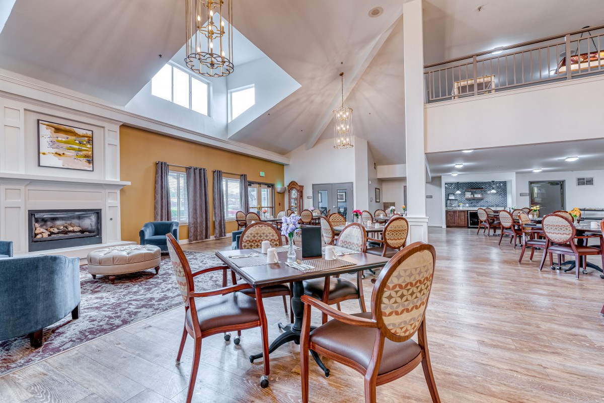 A spacious dining area with elegant furnishings and a vaulted ceiling, illuminated by a large chandelier.