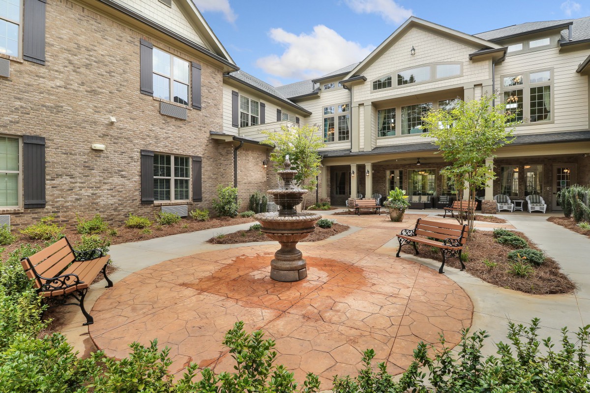 A serene courtyard featuring a central fountain surrounded by benches and well-maintained landscaping.
