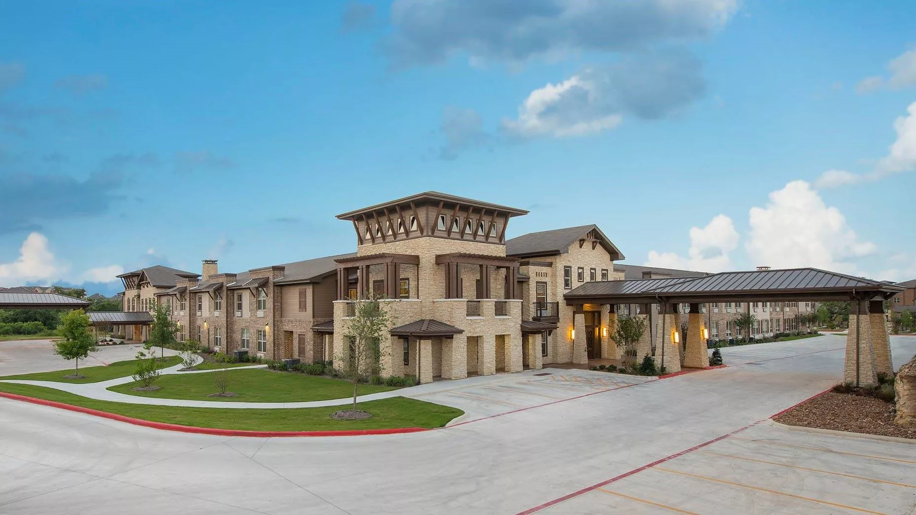 A modern residential building with a spacious driveway and clear sky.