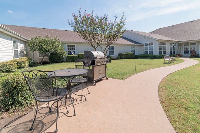 A sunny backyard patio featuring a grill and outdoor furniture.