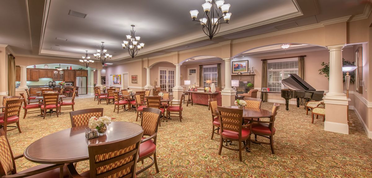 A well-lit dining area with elegant furniture and chandeliers.