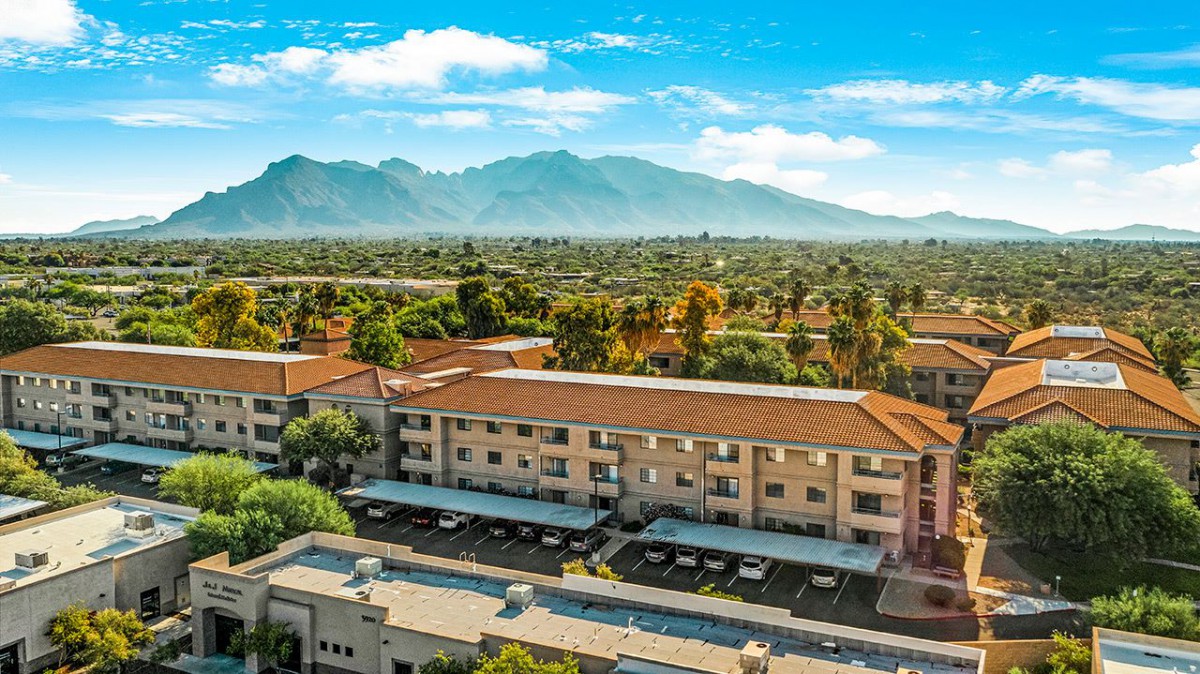 A scenic view of a building complex with mountains in the background on a clear day.