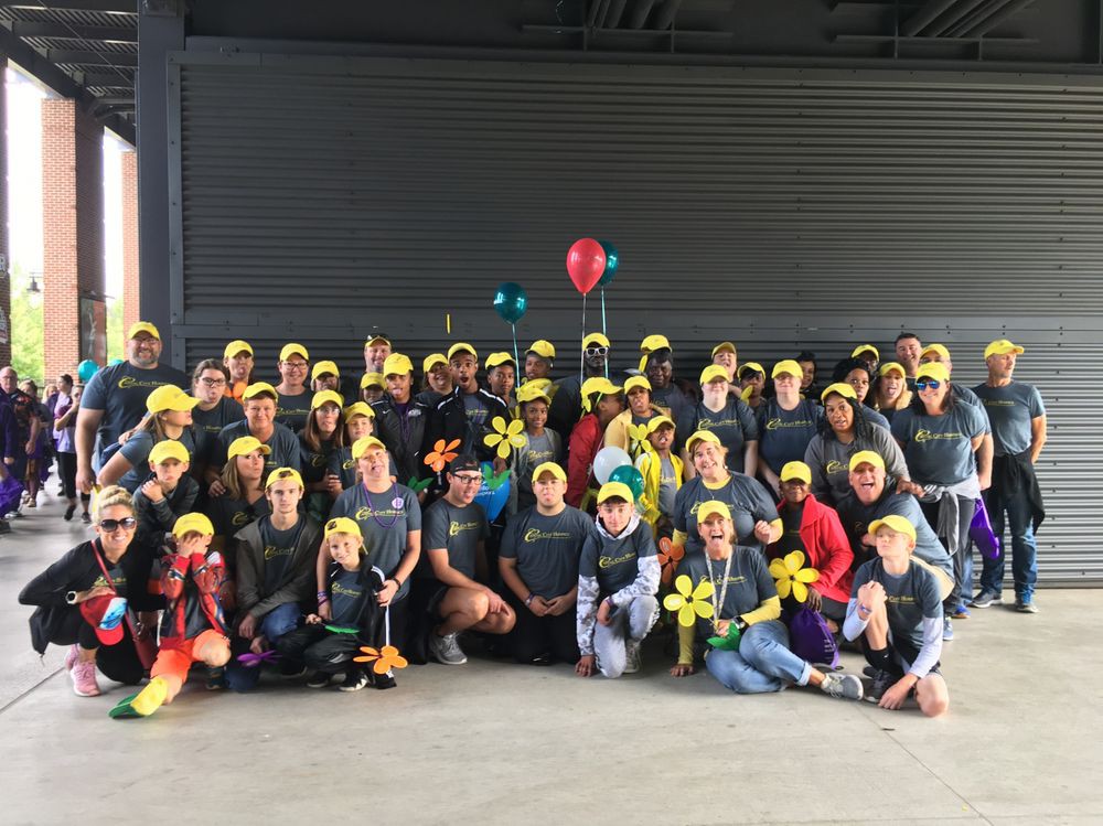 A large group of people wearing yellow hats, gathered indoors with balloons and decorations.