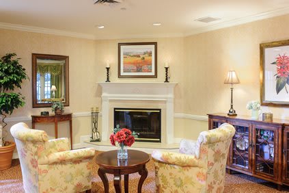 A cozy living room with a fireplace, two armchairs, and elegant decor.