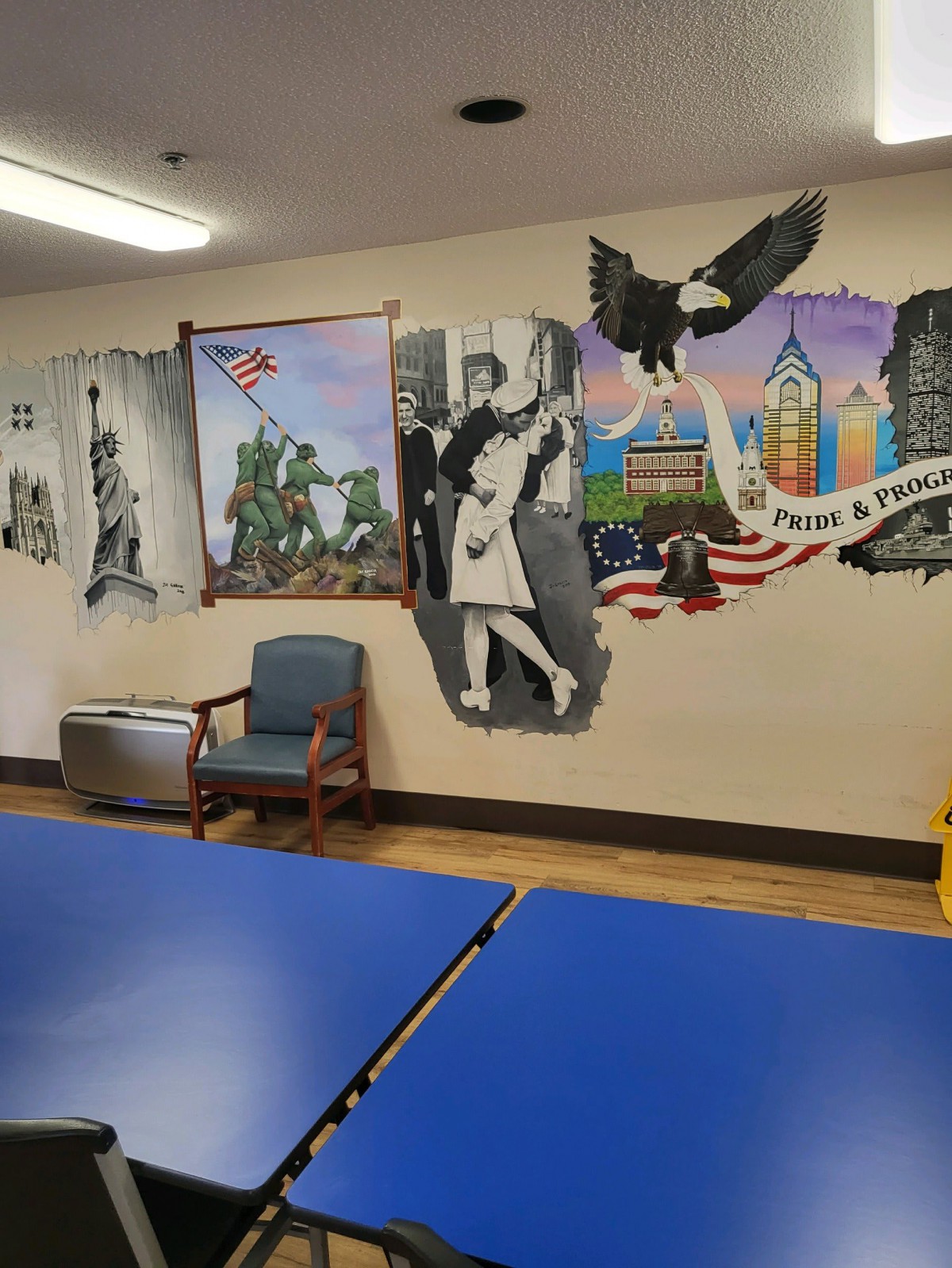 Indoor mural featuring historical images and an eagle on the wall above a table and chair.