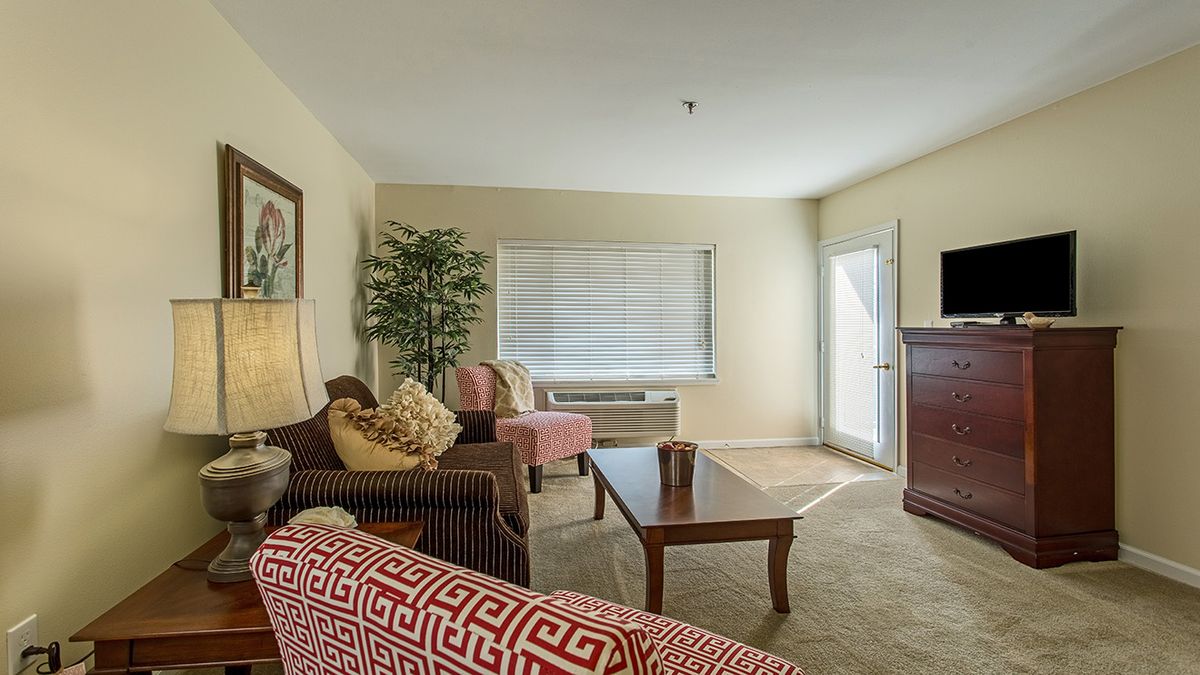 A cozy living room with a neutral color palette, featuring a sofa, armchair, coffee table, and decorative accents.
