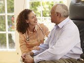 A healthcare professional interacting with an elderly patient at home.