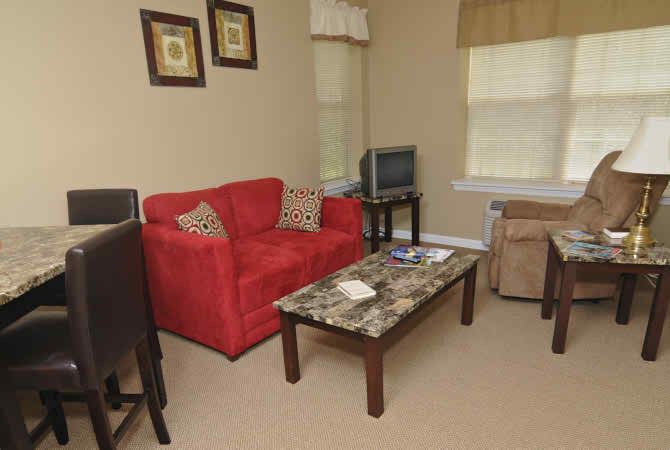 A cozy living room featuring a red sofa, marble-top coffee table, and a small television.