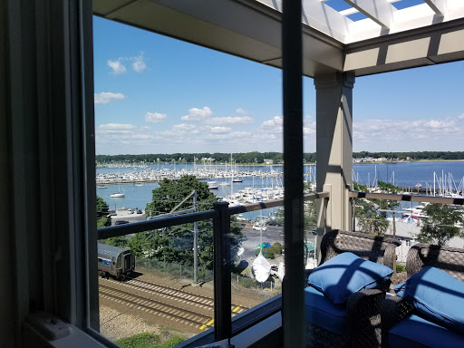 A serene view of a marina lined with boats under a clear blue sky, framed by modern architecture.
