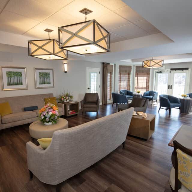 A modern living room featuring stylish furniture, geometric chandeliers, and contemporary artwork.