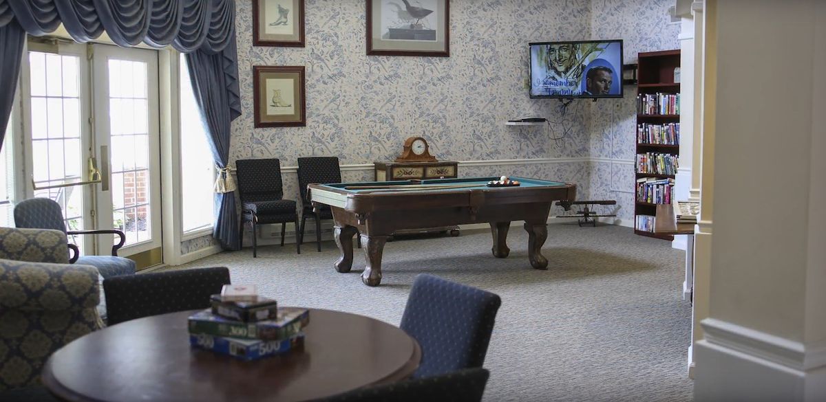 A cozy room with a billiards table, adorned with paintings, a television, and classic furnishings.