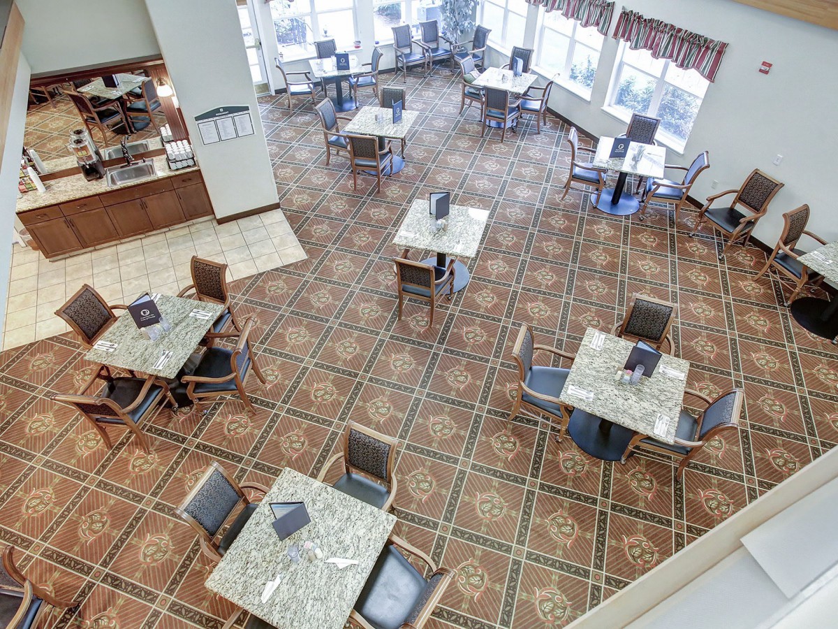 An empty dining area with tables and chairs arranged neatly on a tiled floor.