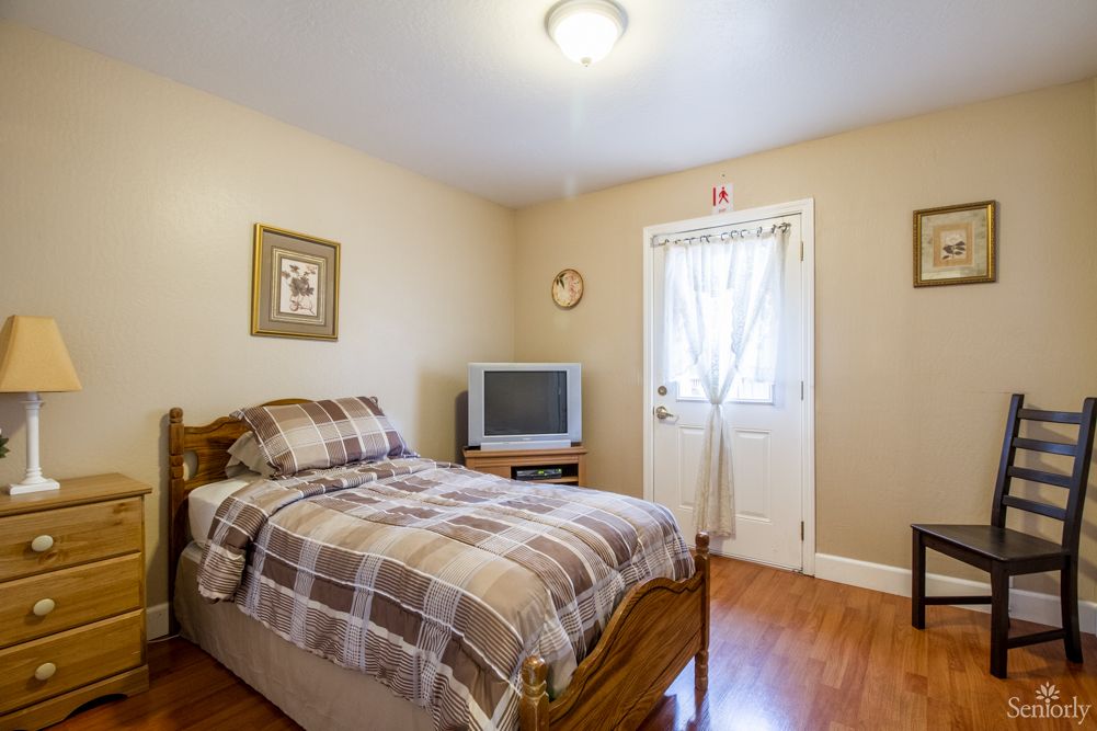 A cozy bedroom with a single bed, a television, and simple decor.