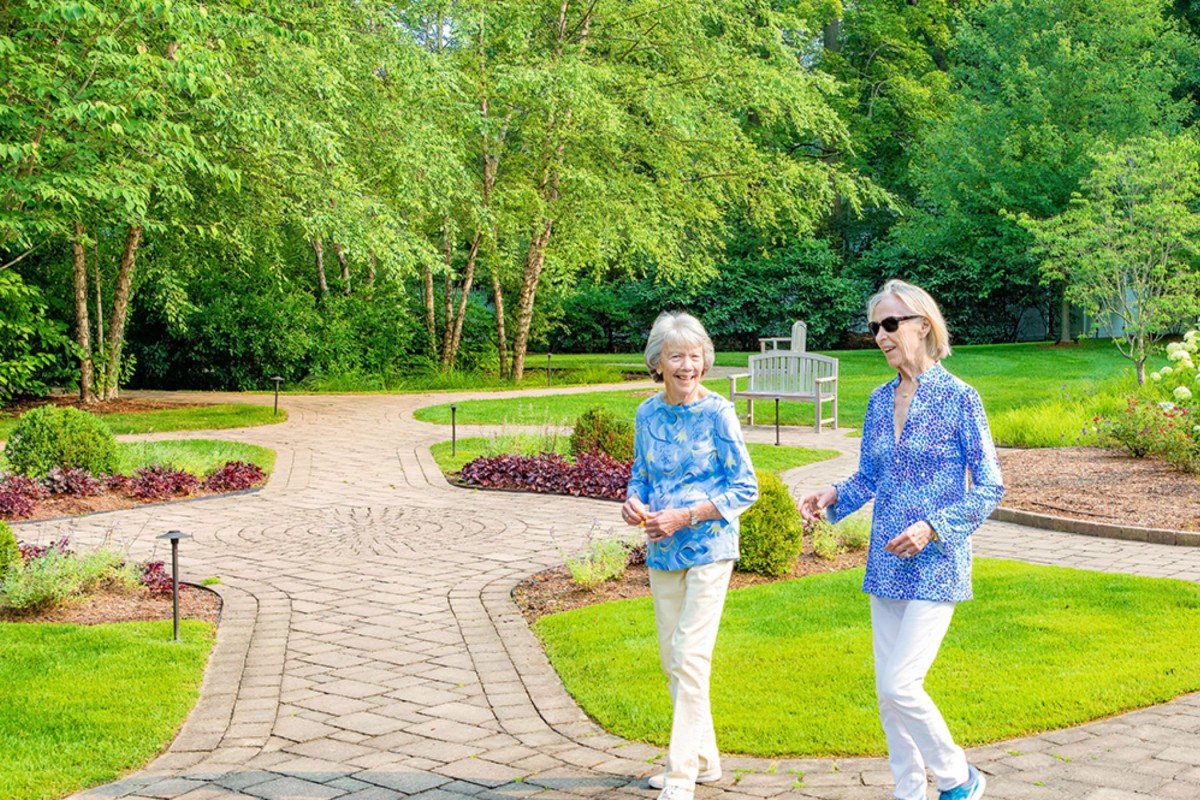 Two people walking along a path in a scenic park setting.