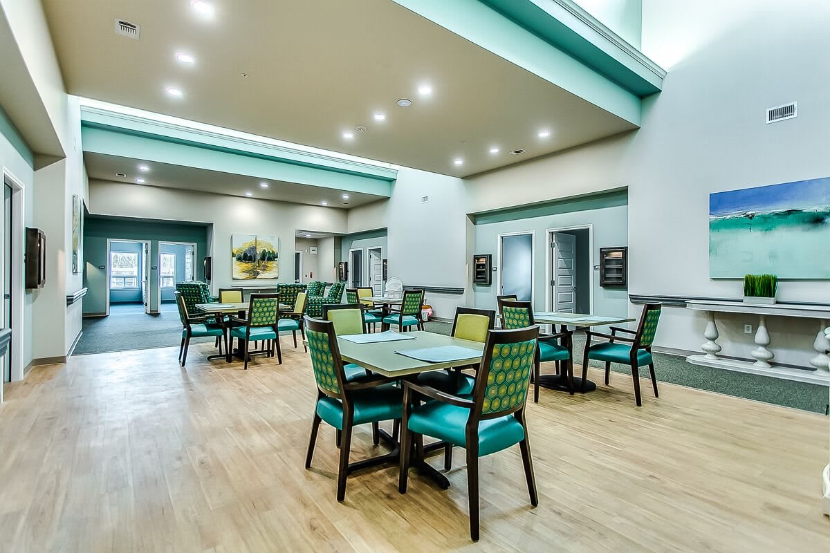 A spacious and modern dining area with several tables and chairs, illuminated by ceiling lights.