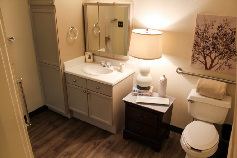 A warmly lit bathroom with a sink, mirror, and lamp.