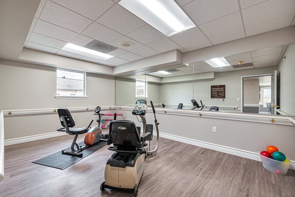 A clean and well-lit exercise room featuring gym equipment and large mirrors.
