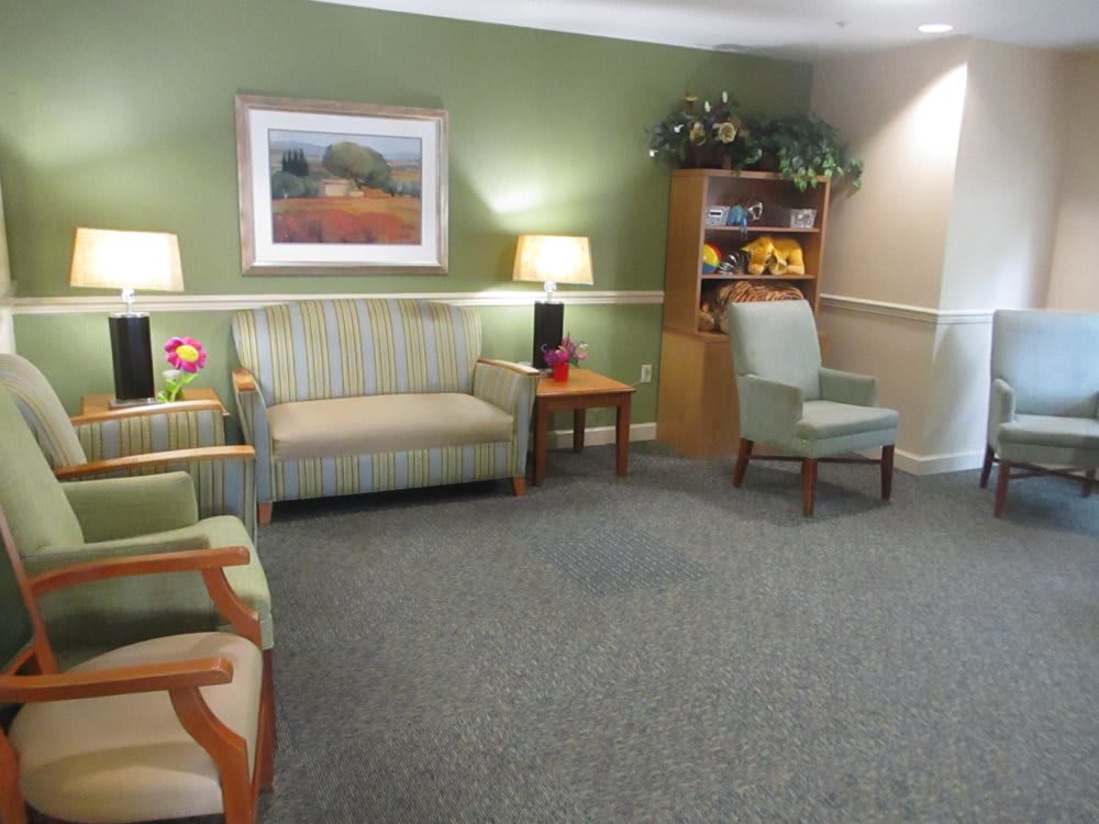 A cozy living room with sofas, chairs, and a bookshelf, decorated in warm tones.