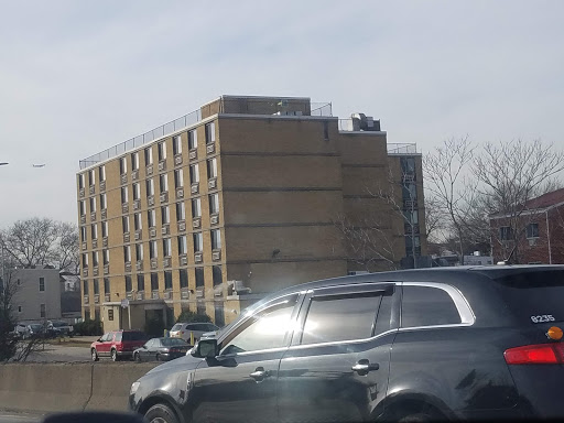 A view of a building alongside a busy highway, with a car in the foreground.